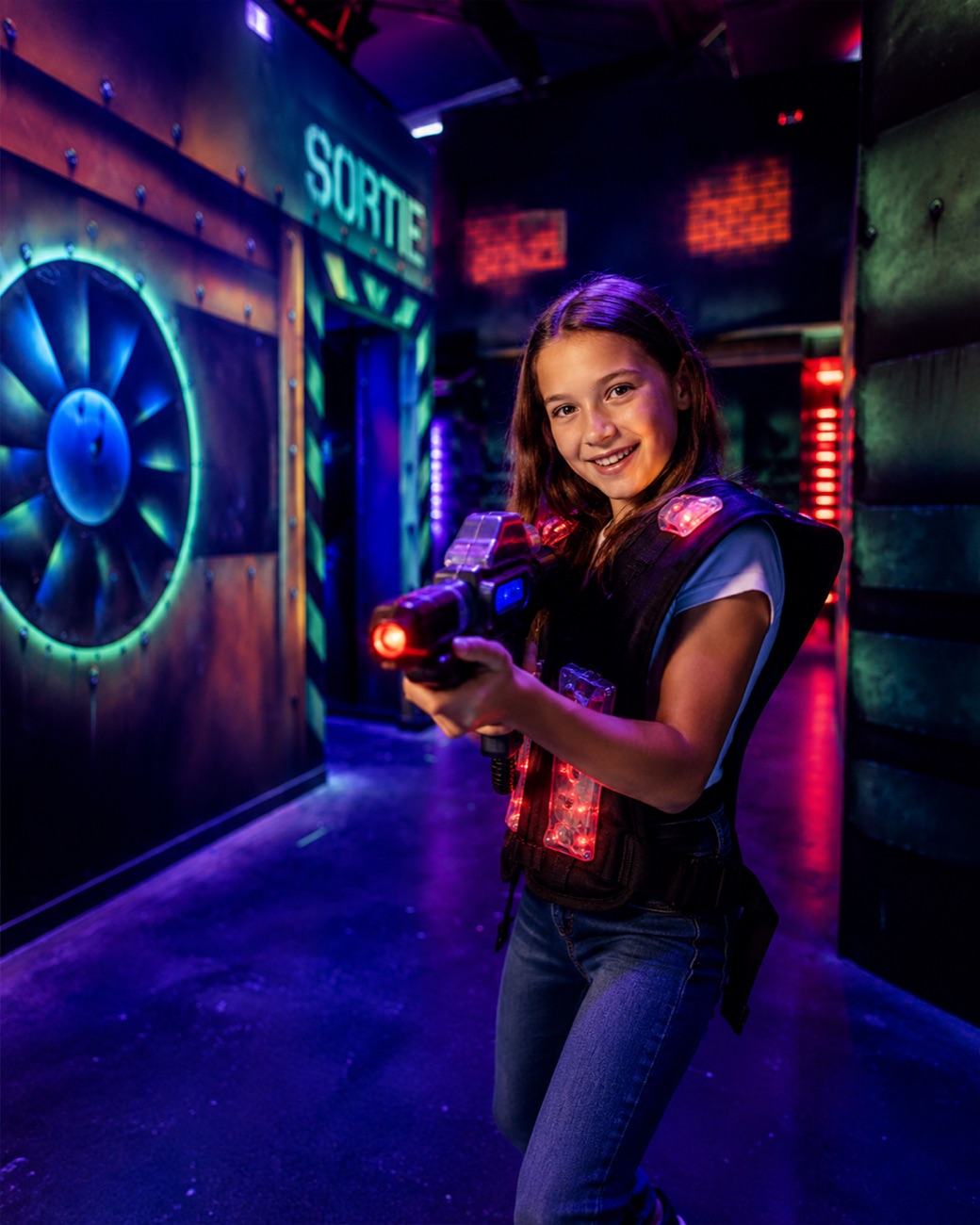 Joueuse équipée pour une partie de laser game dans l'arène immersive du Complexe de Loisirs de Toulouse Montaudran